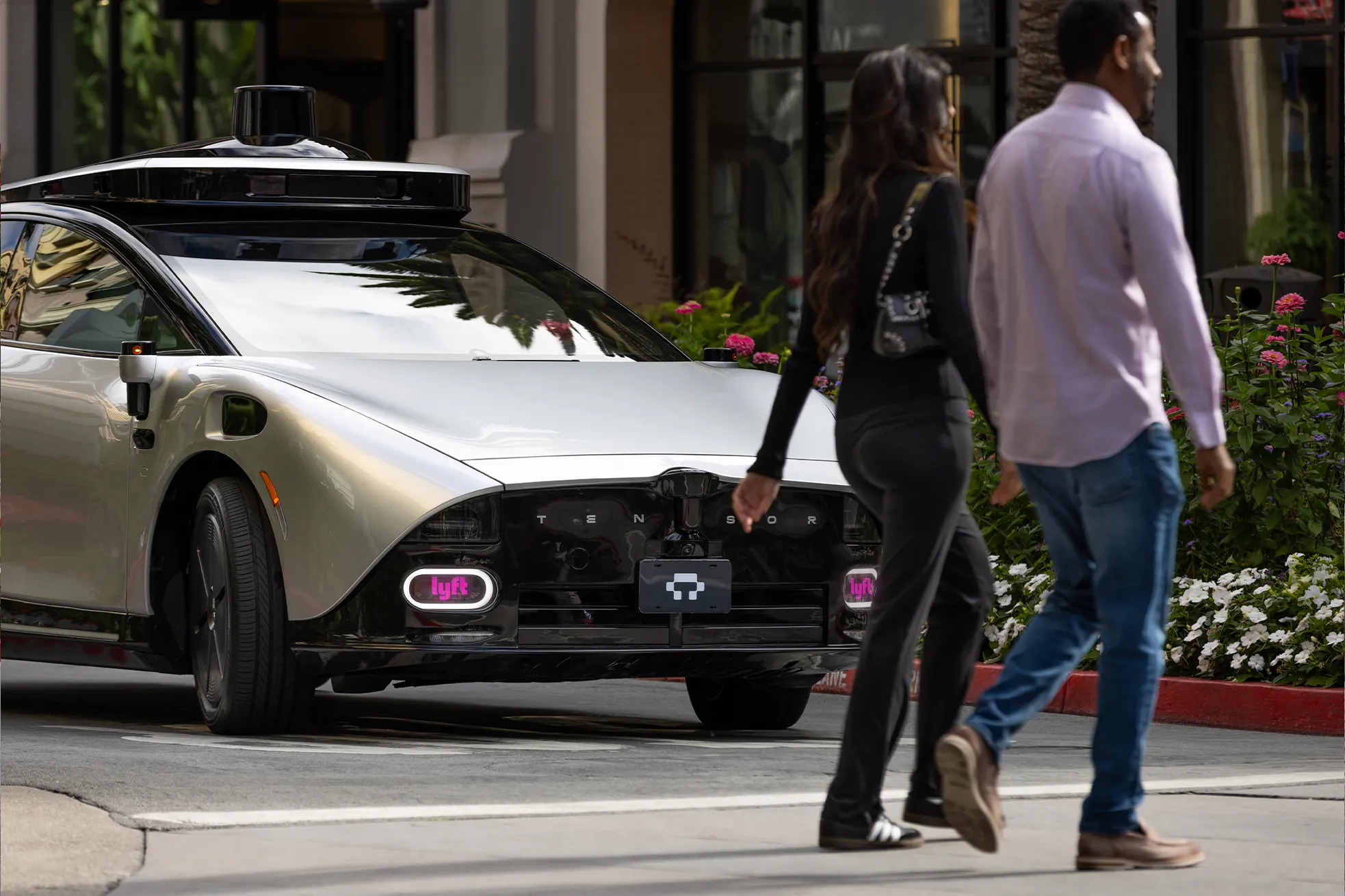 Two pedestrians cross in front of a Tensor Robocar. Photorealistic rendering.