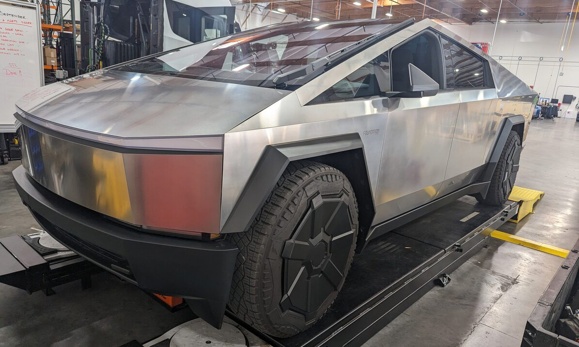 A Tesla Cybertruck sits on a lift in a service warehouse.