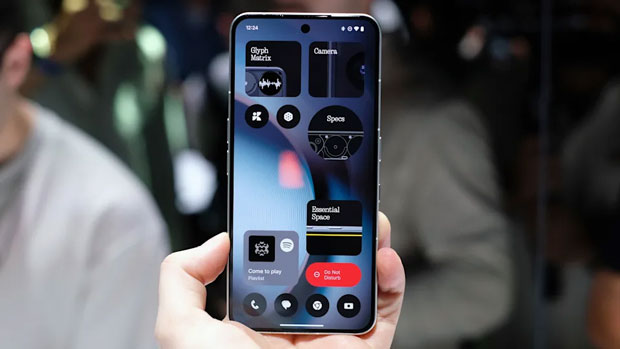Image of the Nothing Phone 3 held in a hand in front of a dark bokeh background of a crowd of people.