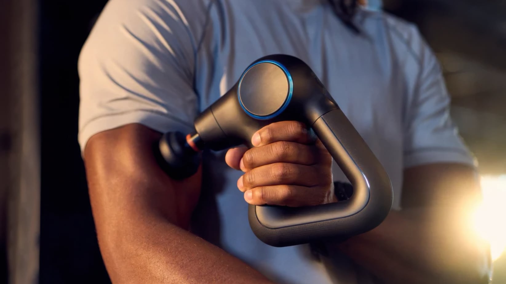 Closeup of a massage gun on a person's bicep.