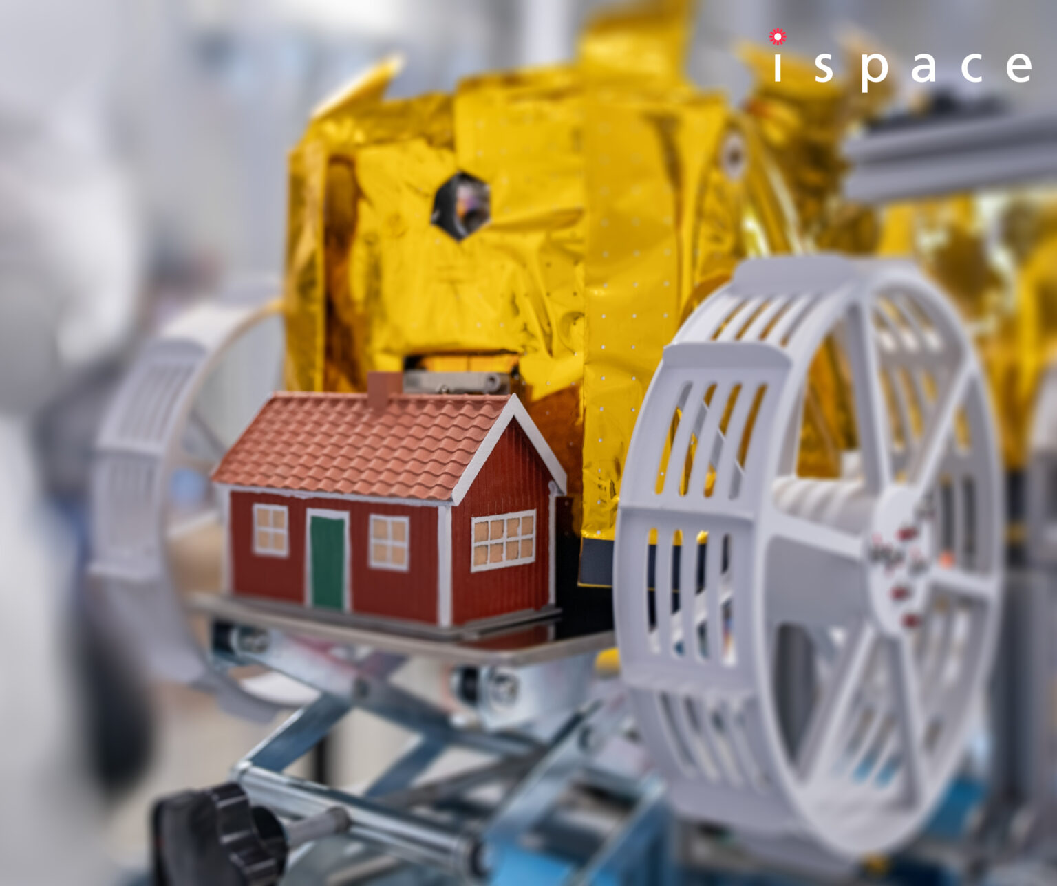 The tiny model red house, Moonhouse, is shwn mounted on ispace's lander