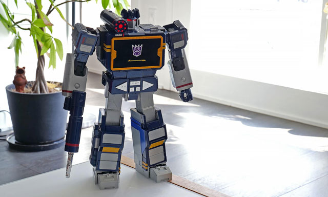 Image of the Robosen Soundwave standing in front of a plant.