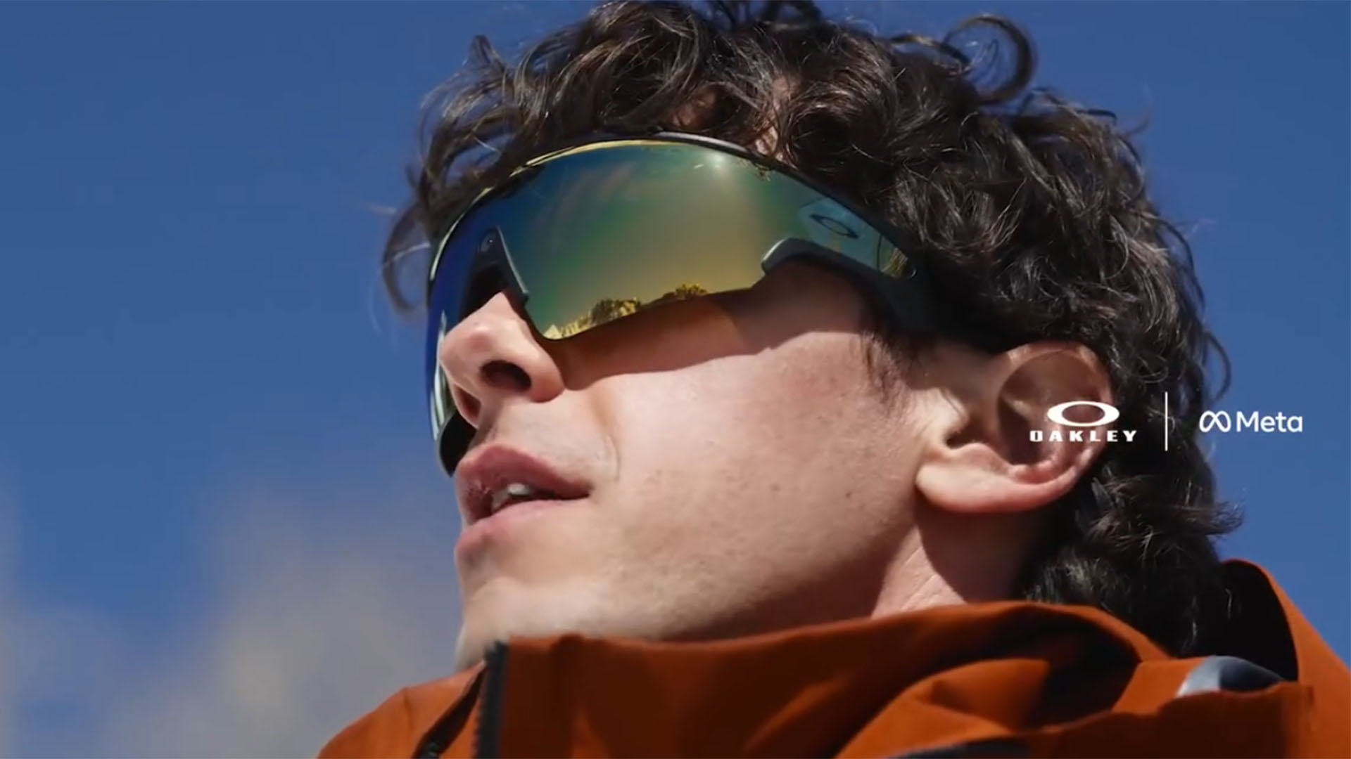 A closeup of a person wearing Oakley wraparound sunglasses, with a single camera visible in the center of the frames.