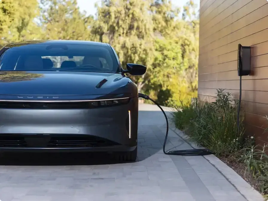A Lucid Air sedan, charging in a driveway.