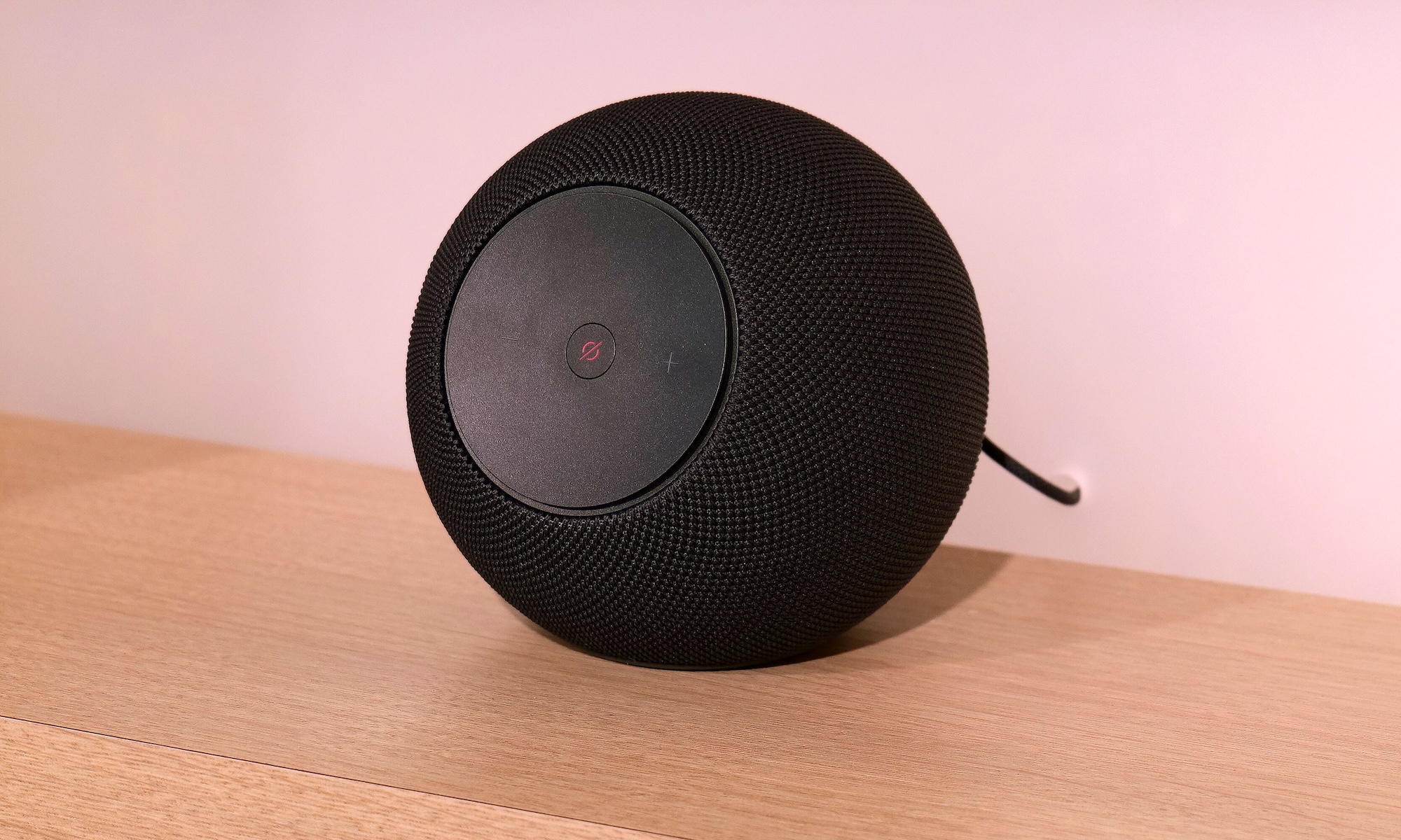 The new Amazon Echo Studio sits on a brown shelf.