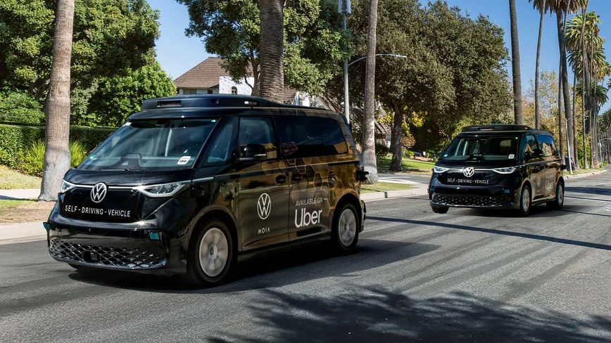 Two autonomous VW ID. Buzz microvans on a suburban street