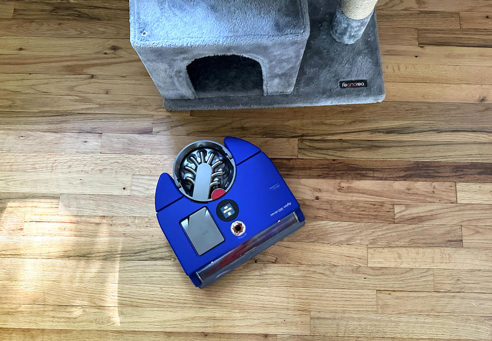 Top-down photo of the purple robovac, cleaning a floor next to a cat post.