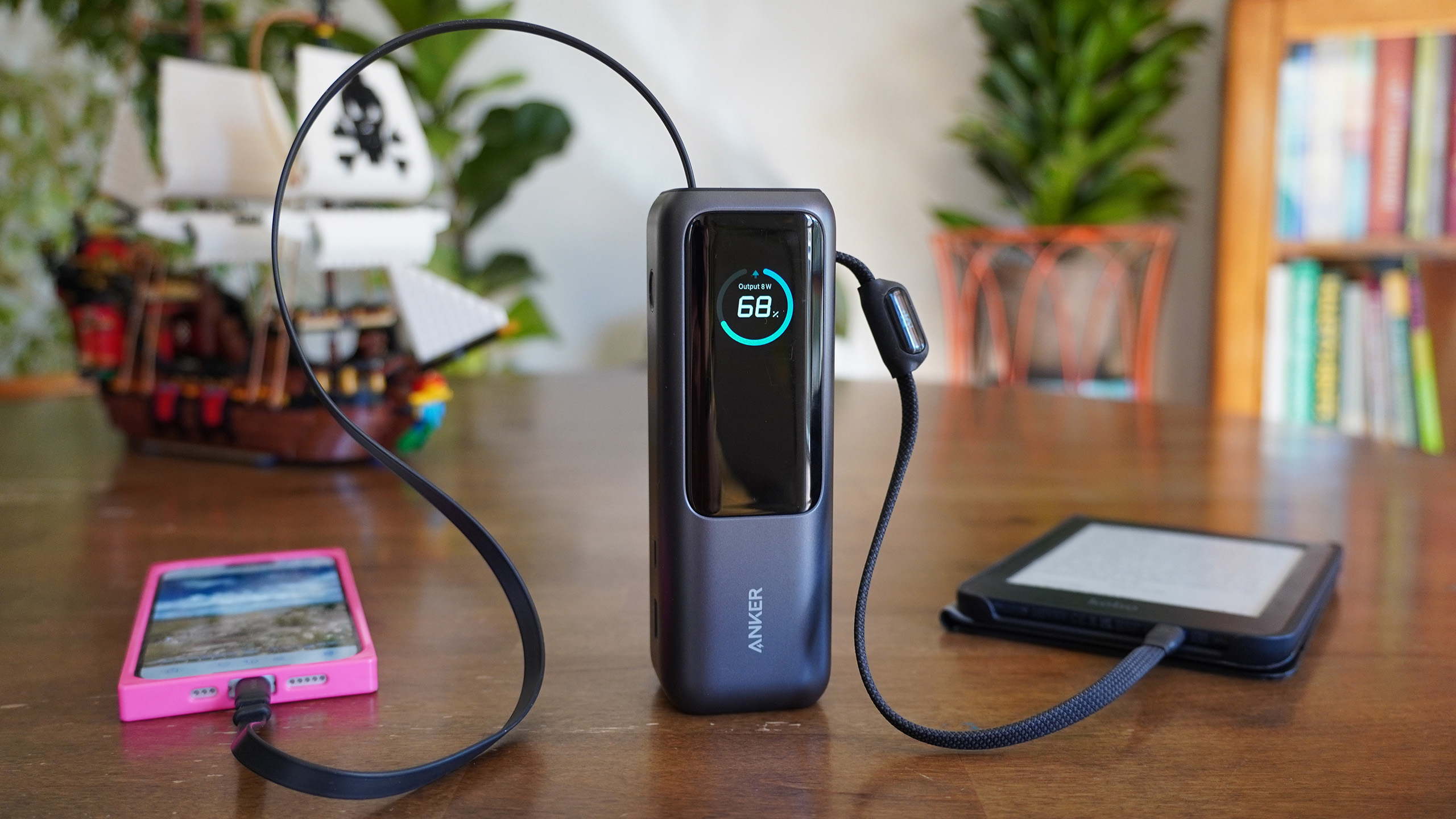 the Anker Laptop Power Bank 25K 165W sits on a table as it charges an iphone and an ereader