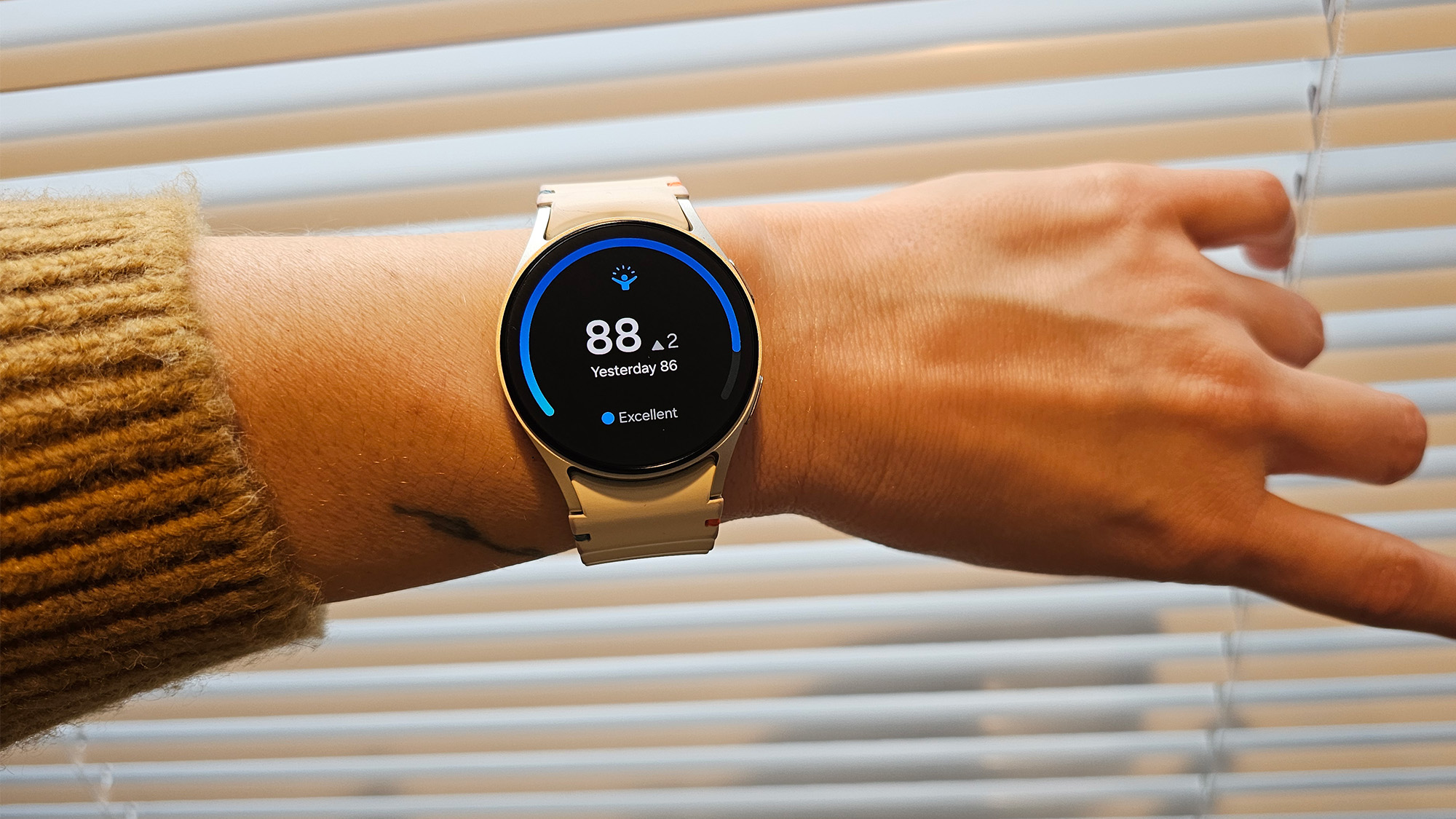 a person wears the Samsung Galaxy Watch 7 in front of some mini blinds
