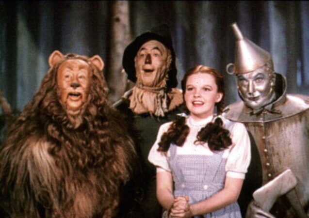 A still from The Wizard of Oz, featuring Dorothy, The Cowardly Lion, Scarecrow and the Tin Man.