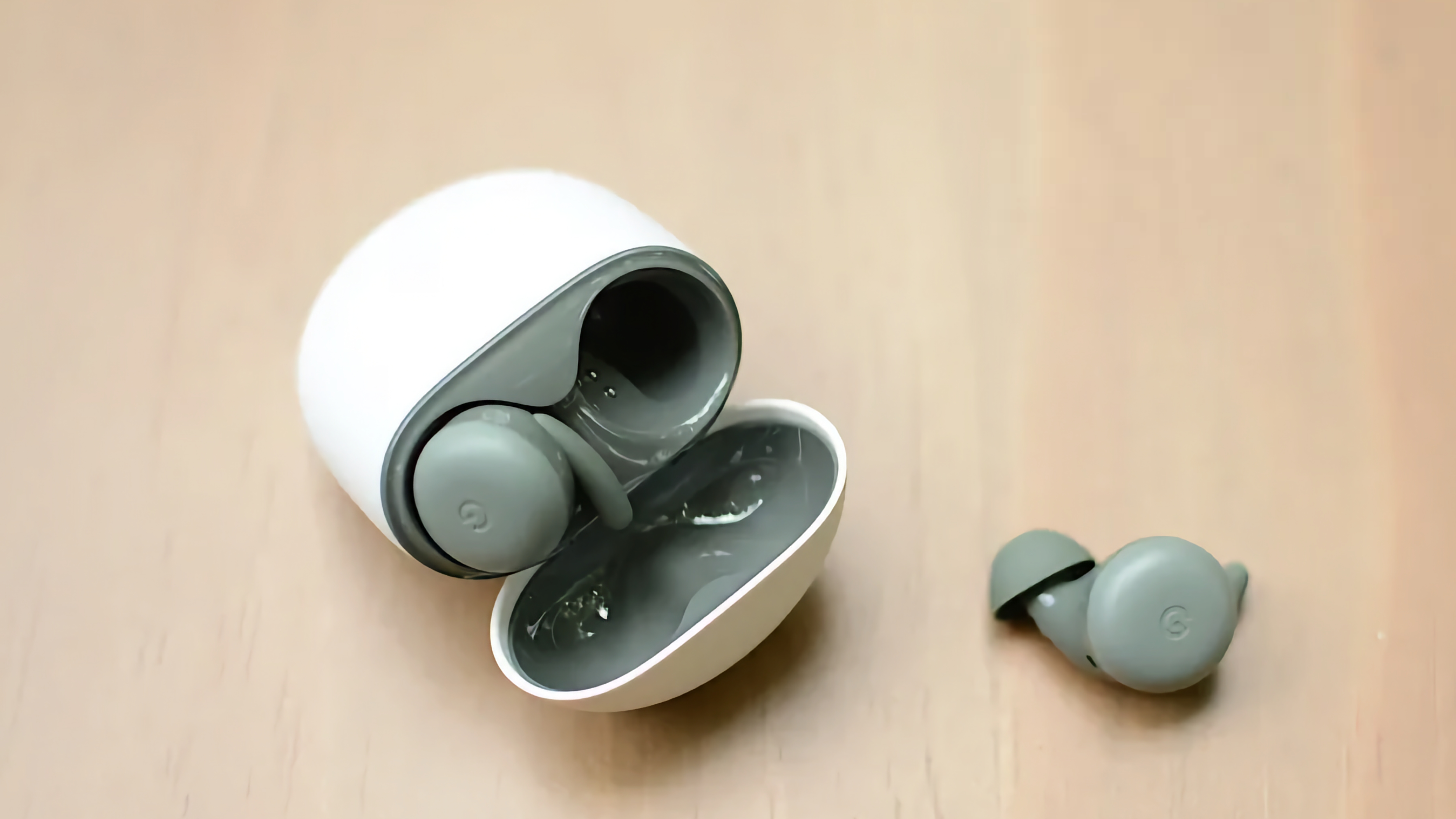 The green Pixel Buds A-Series wireless earbuds with their case open and one earbuds popped out.