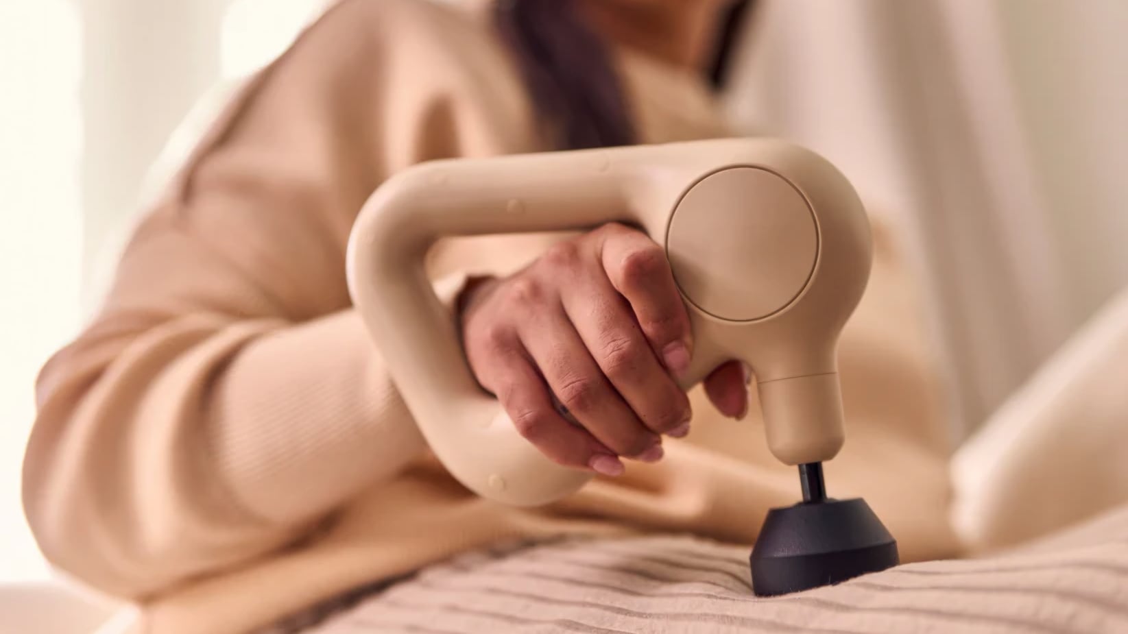 Closeup of a massage gun on a person's thigh.