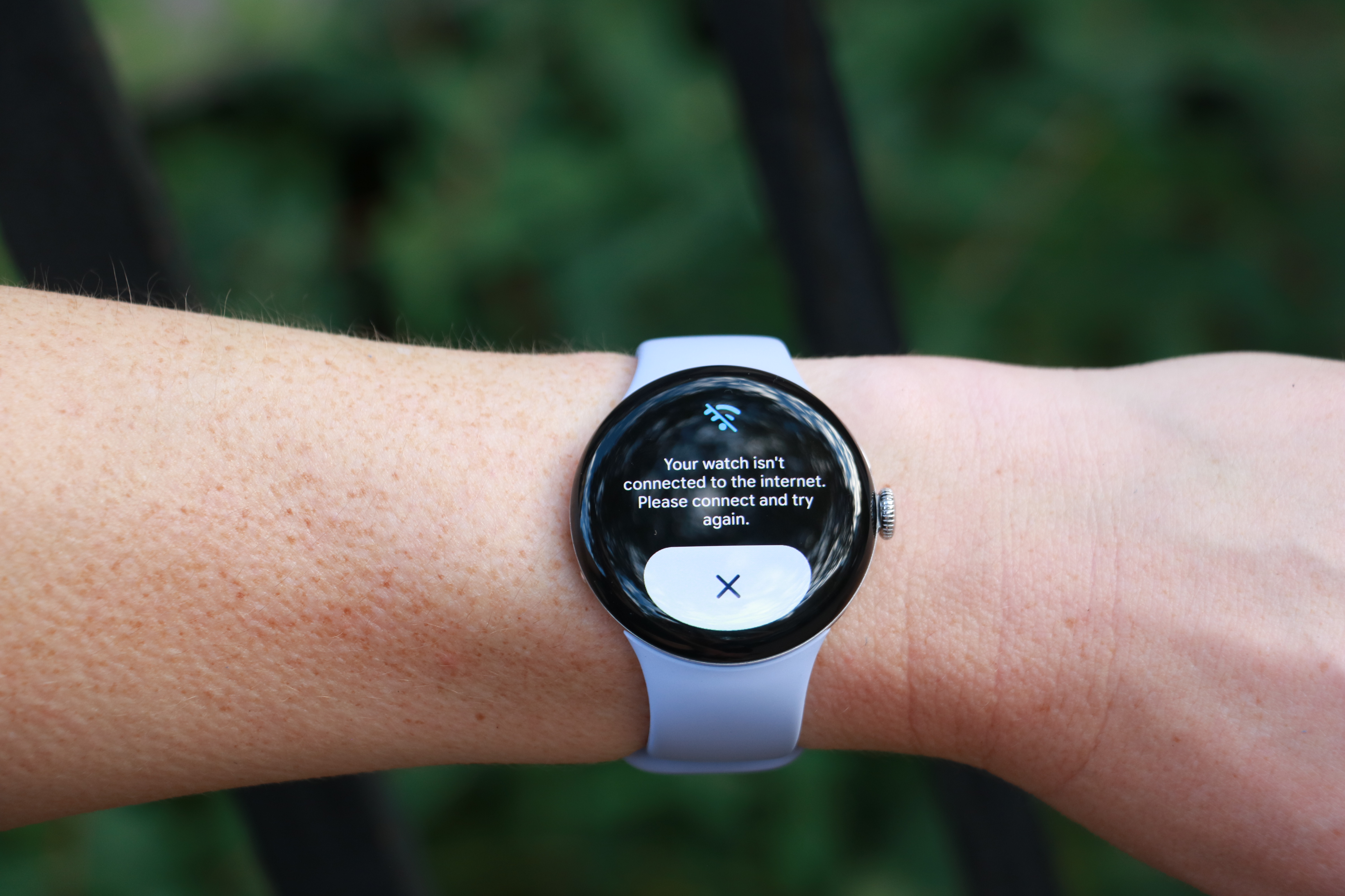 The Pixel Watch 4 on a wrist held up in mid-air, with its screen saying 