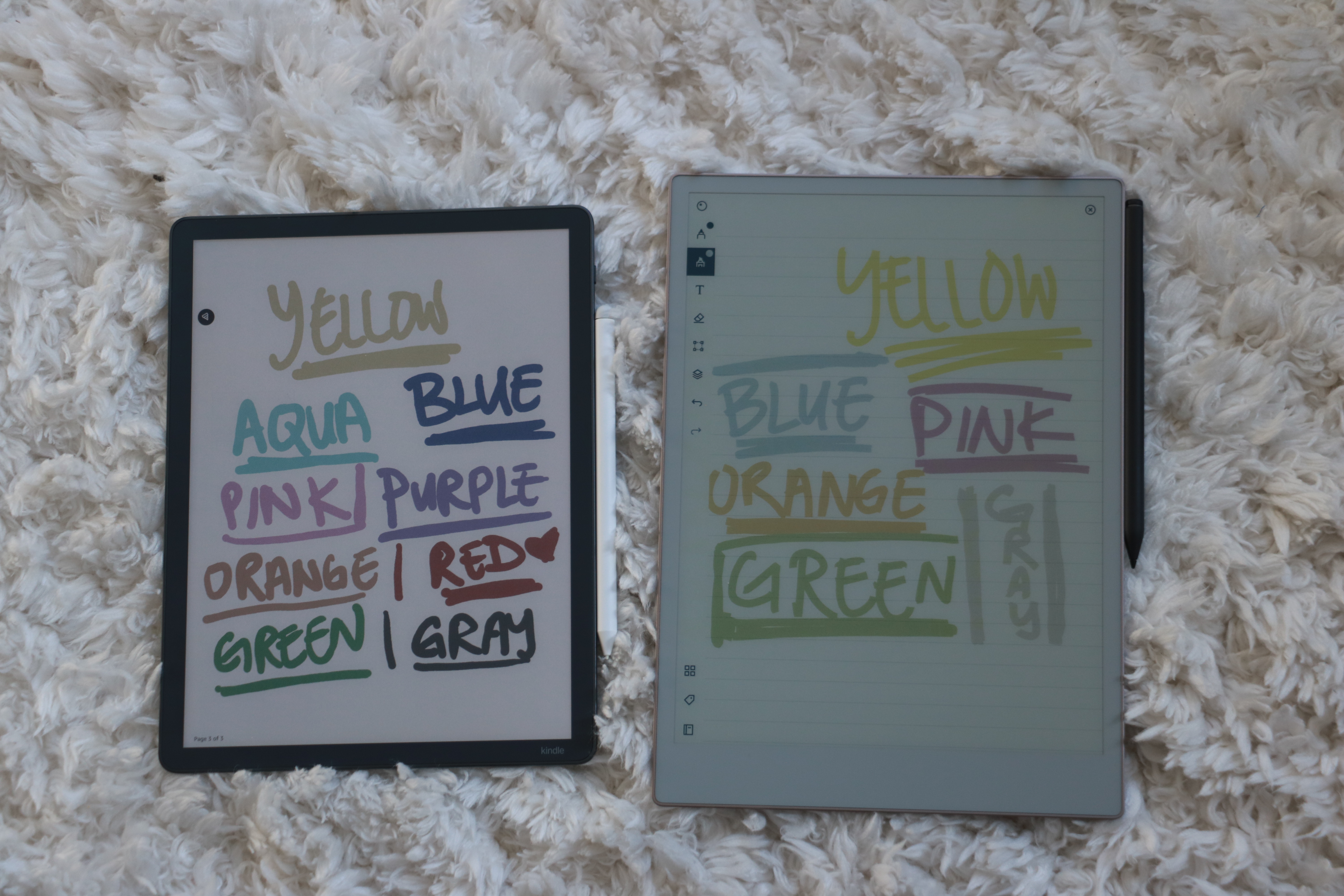 The Amazon Kindle Scribe Colorsoft and reMarkable Paper Pro laid side by side on a furry surface, with each device displaying words written in the colors they represent. The word 