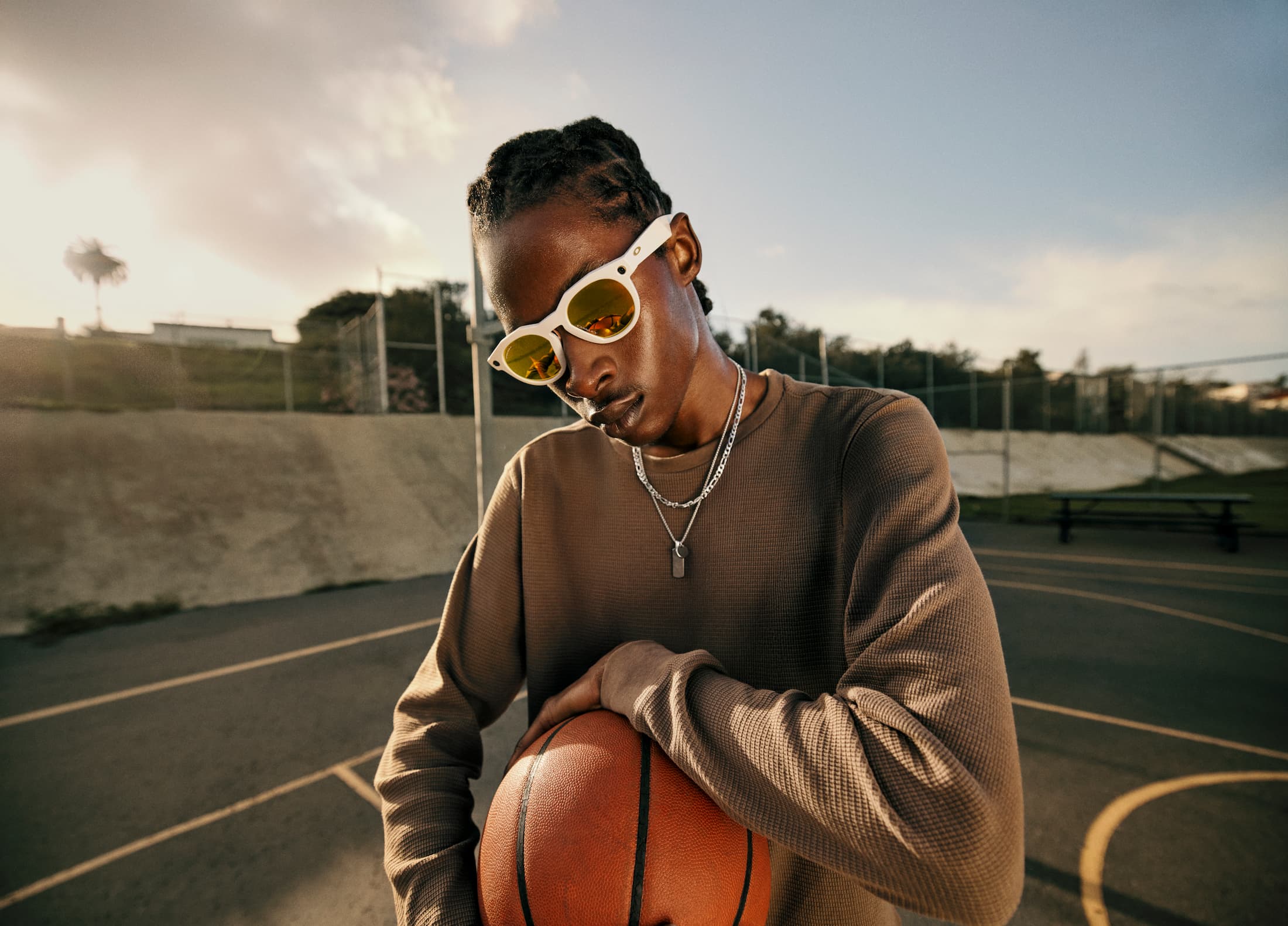 A person wearing Oakley Meta HSTN smart glasses and holding a basketball.