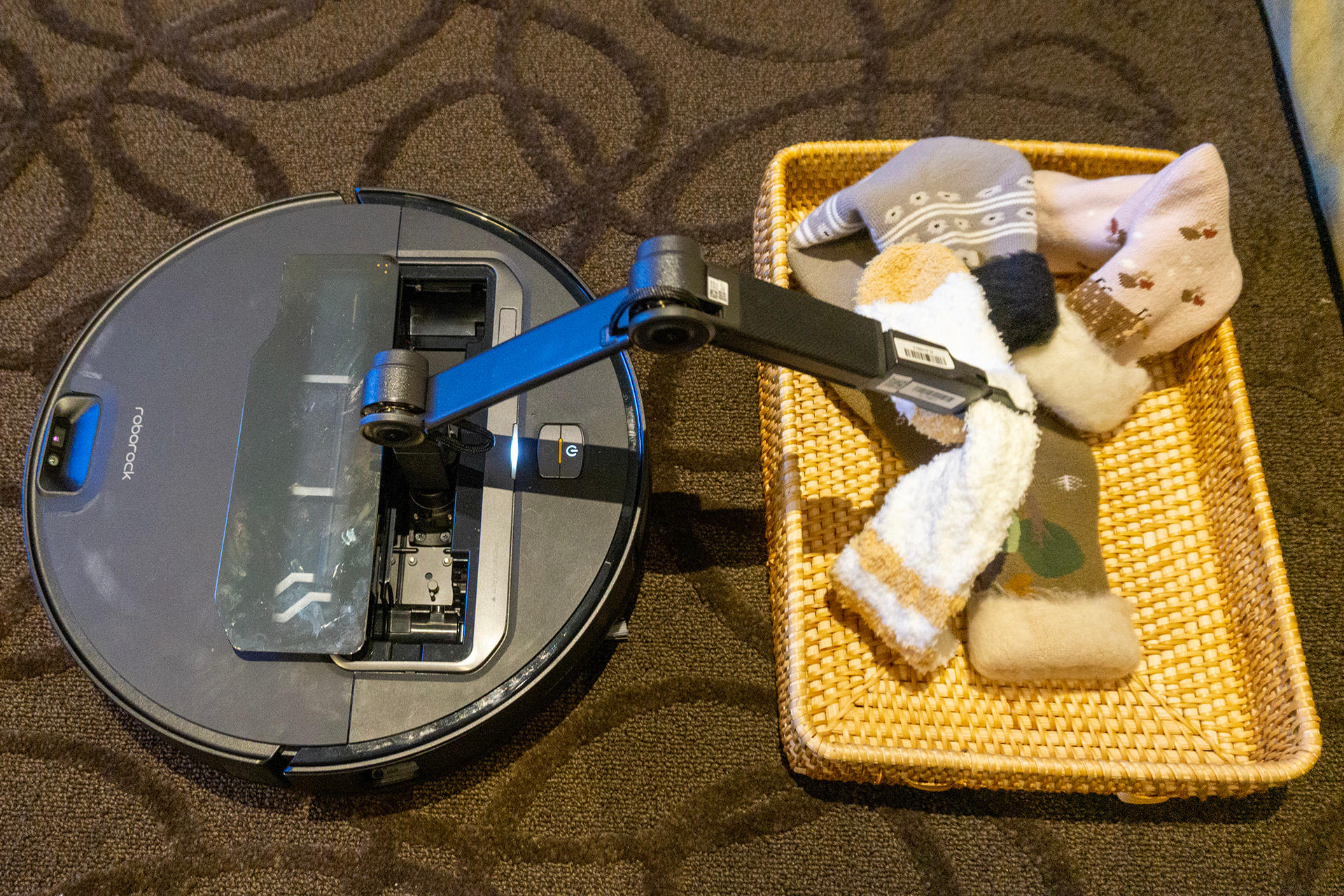 The Roborock Saros Z70 uses its robotic arm to put a handful of socks into a basket. 