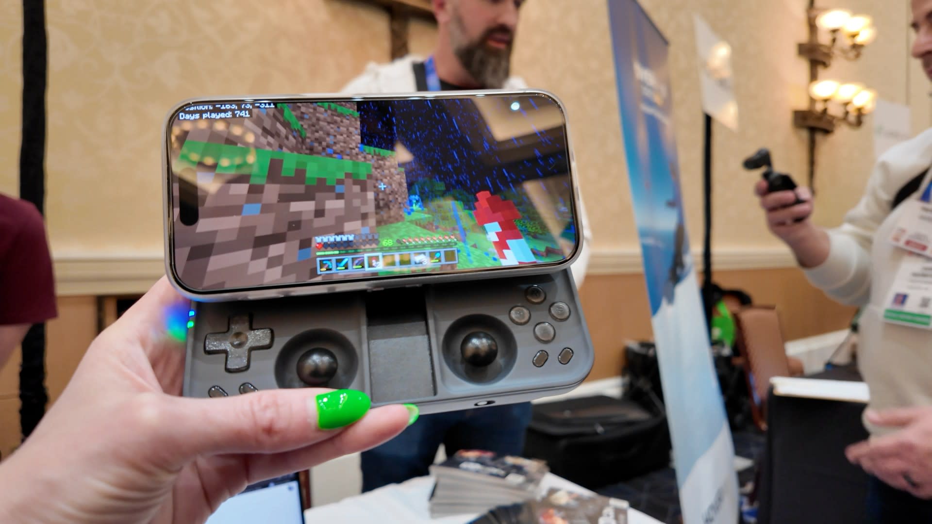 Engadget senior reporter Jessica Conditt holds the OhSnap MCON in her hand at CES 2025. The attached phone displays Minecraft.