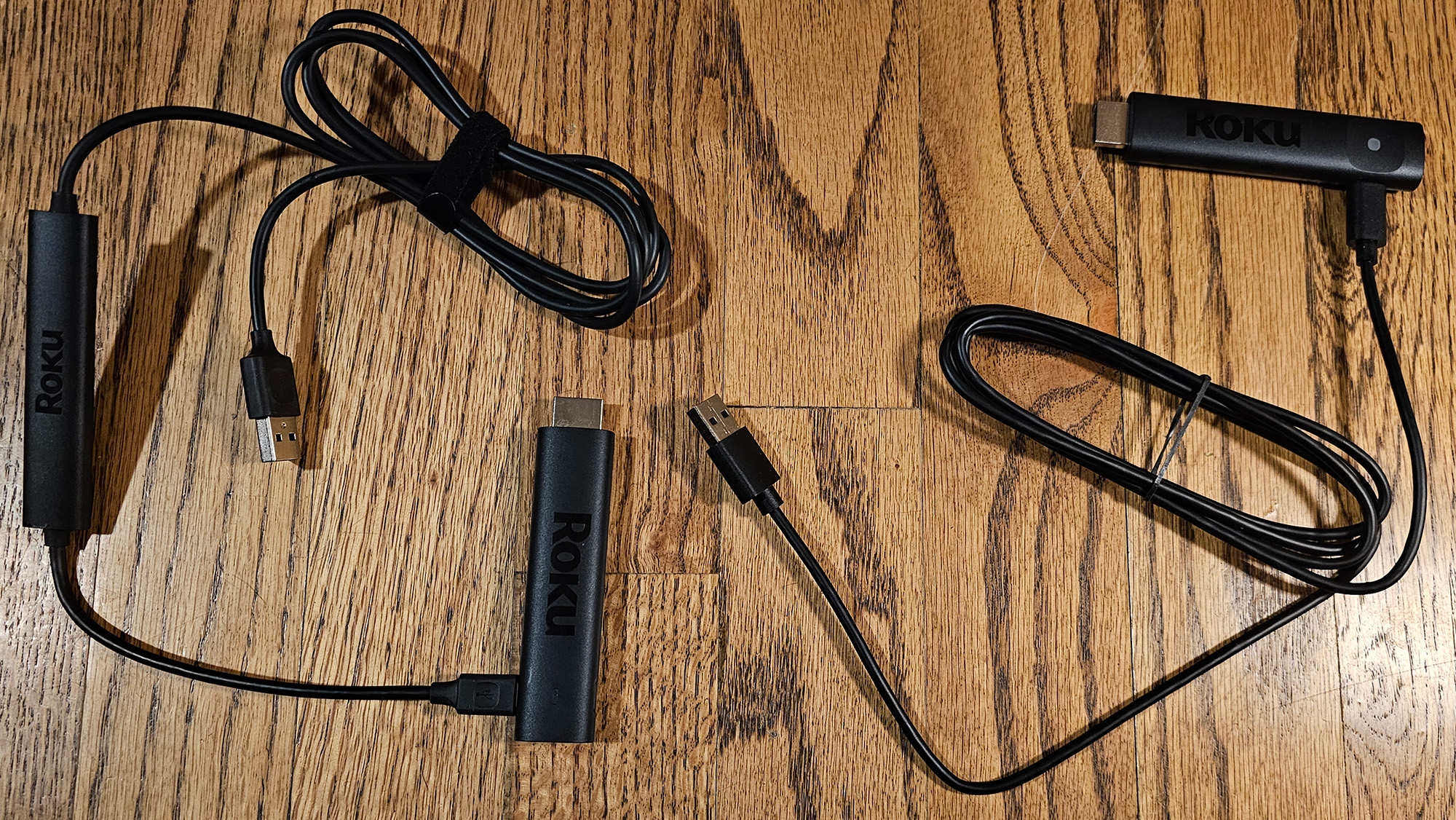 The Roku Streaming Stick Plus dongle and cable next to the Roku Streaming Stick 4K dongle and cable