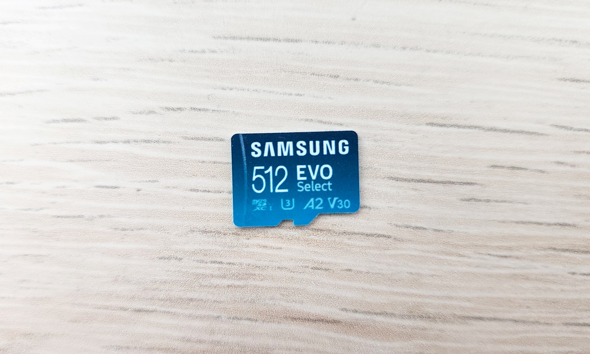 A blue, 512GB version of Samsung's Evo Select microSD card resting on a beige desktop.