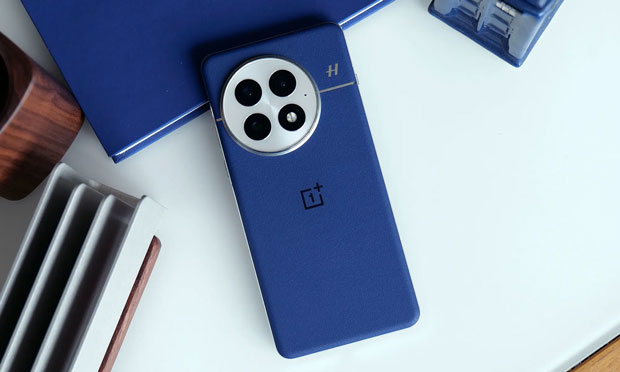 Image of the back of a OnePlus 13, in blue, on a white table. Image of the back of a OnePlus 13, in blue, on a white table.